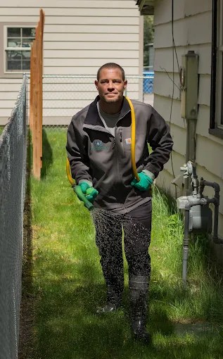 Handsome man spraying fertilizer on a yard in the summer time