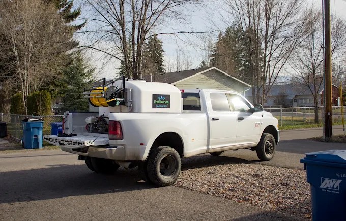 White work truck for Fertilization parked in the morning sun during a job.